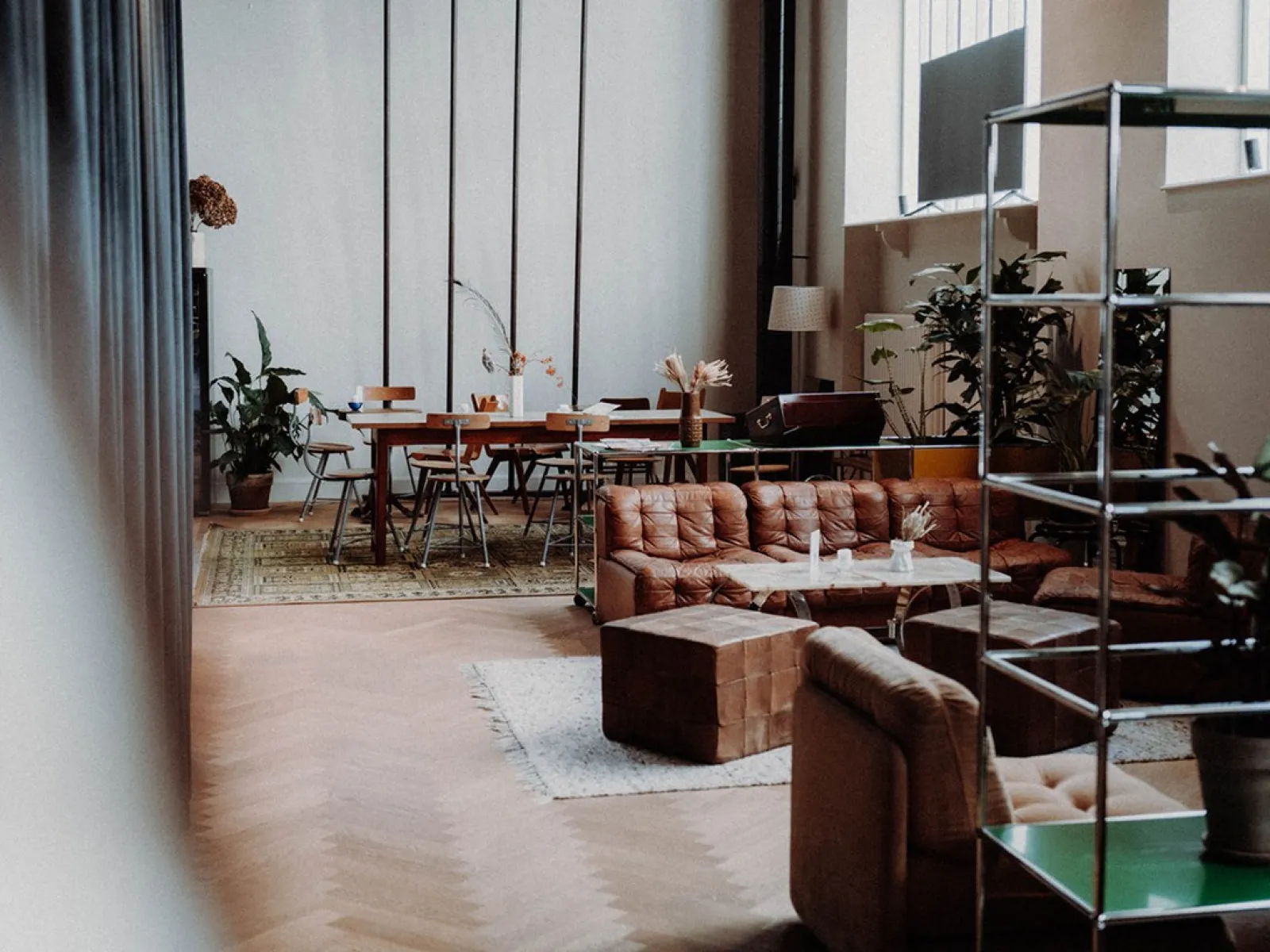 Gemütlicher Raum mit Sofas, Pflanzen und einem großen Tisch, ideal für Treffen und Networking-Veranstaltungen.