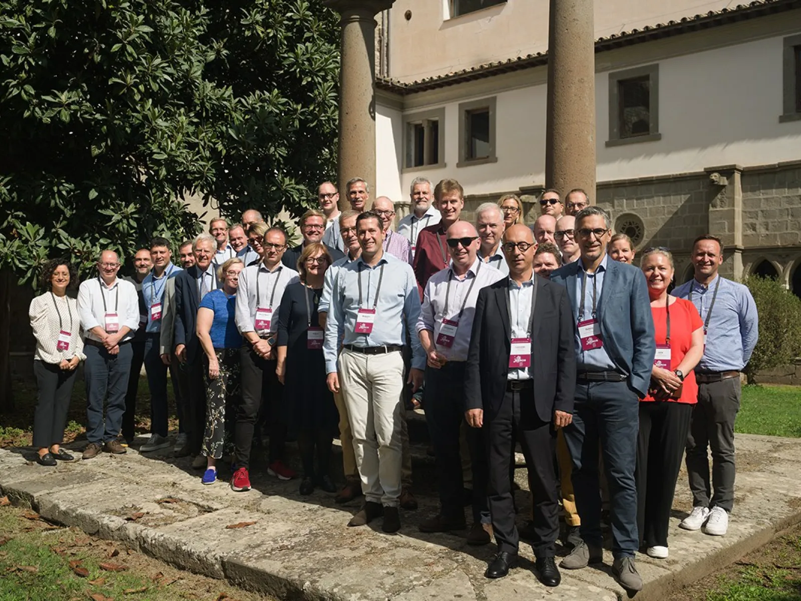 Gruppe von Menschen steht draußen vor einem historischen Gebäude während des ERCIS-Workshops in Viterbo, Italien. Sie tragen Namensschilder und lächeln in die Kamera.