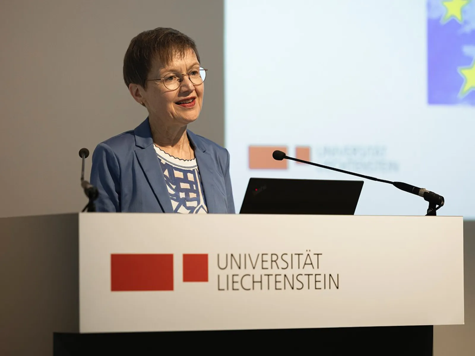 Eine Frau steht am Rednerpult im Auditorium der Universität Liechtenstein. Vor ihr steht ein Laptop, hinter ihr ist eine Präsentation zu sehen.