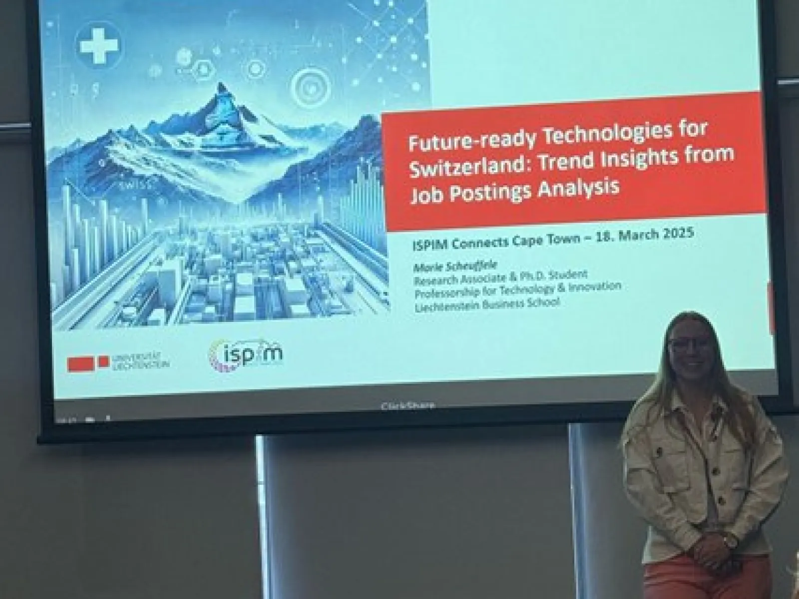 Eine Person steht vor einer Präsentationsfolie mit dem Titel "Future-ready Technologies for Switzerland: Trend Insights from Job Postings Analysis". Die Folie zeigt ein futuristisches Bild von Bergen und einer Stadt. Die Präsentation fand am 18. März 2025 in Kapstadt statt.