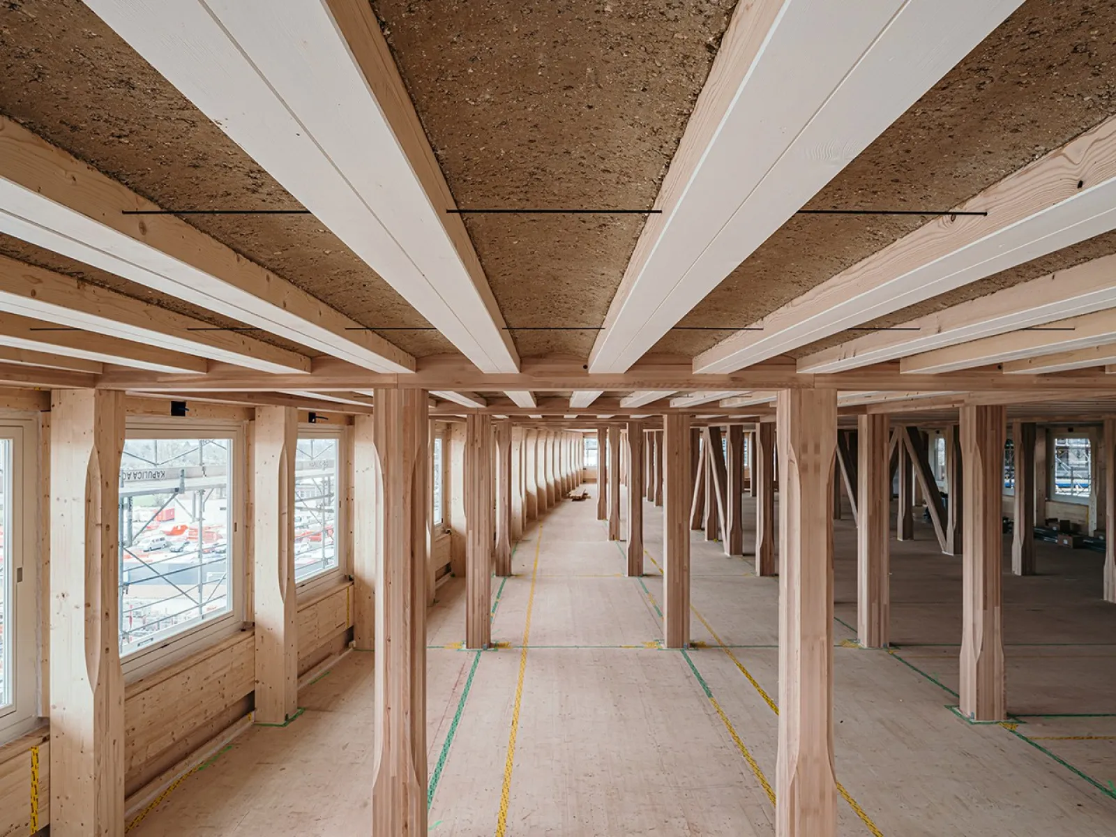 Innenansicht eines modernen Gebäudes mit Holzkonstruktion und Lehmboden, das den nachhaltigen Lehmbau am EARTH HUB der Universität Liechtenstein zeigt.