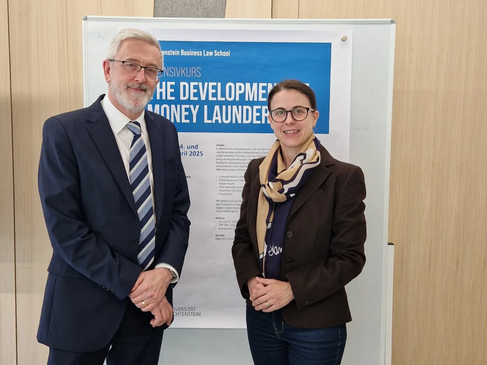 Zwei Personen stehen vor einem Poster des Intensivkurses „The Development of Money Laundering“ an der Universität Liechtenstein.