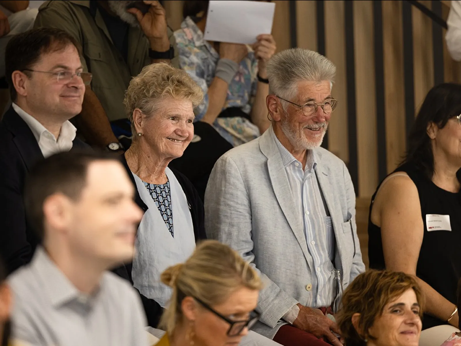 Eine Gruppe von Menschen sitzt lächelnd in einem Auditorium während des Tags der offenen Tür an der Universität Liechtenstein.