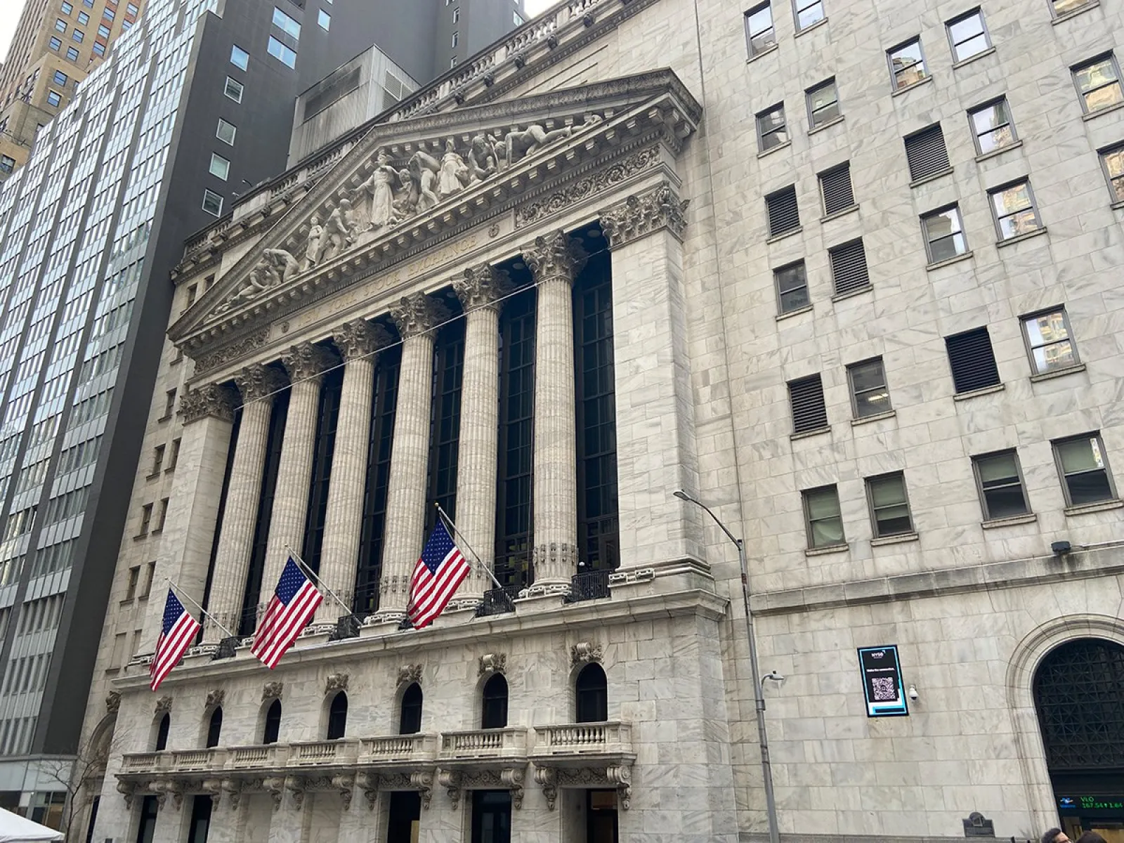 Außenansicht der New York Stock Exchange mit amerikanischen Flaggen, symbolisiert das globale Finanzzentrum und die moderne Finanzwirtschaft.