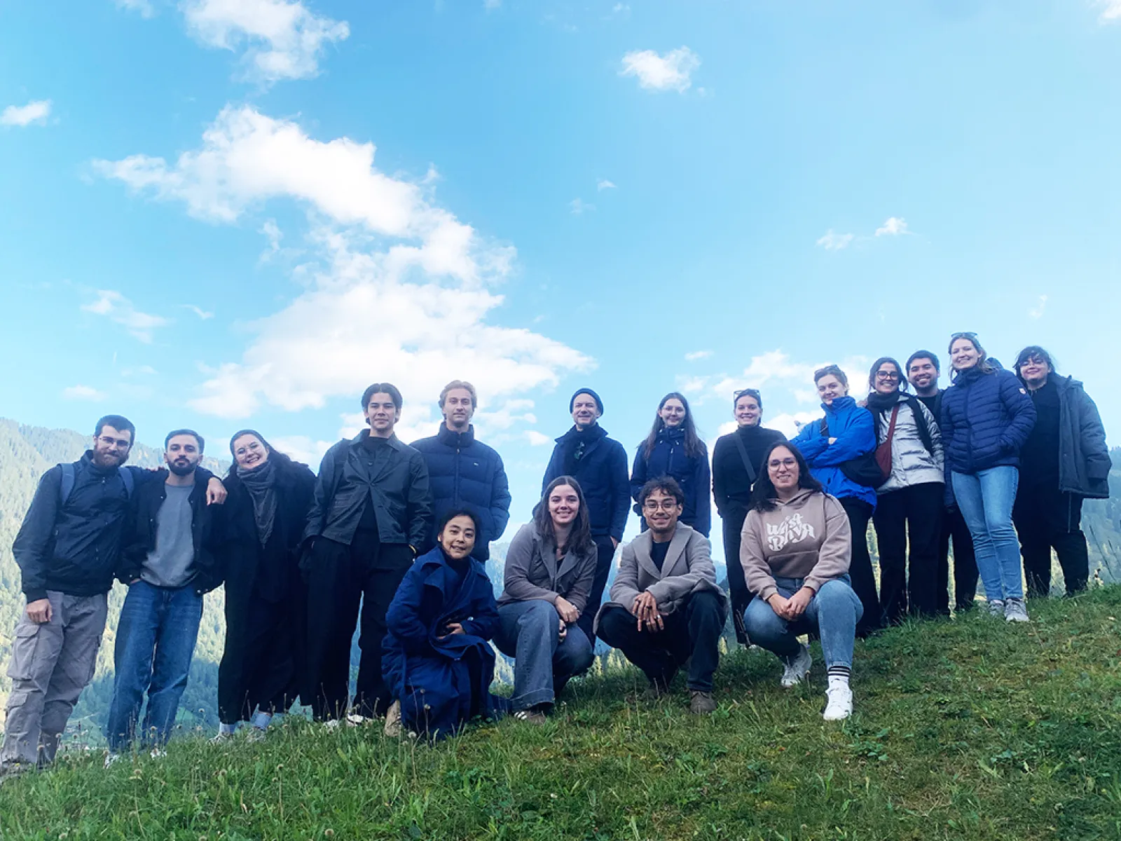 Gruppenfoto junger Studierender mti blauem Himmel und grüner Wiese