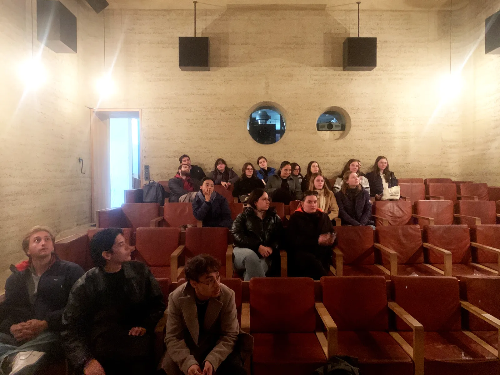 Junge Menschen in einem Kino aus Stampflehm mit braunen Ledersesseln