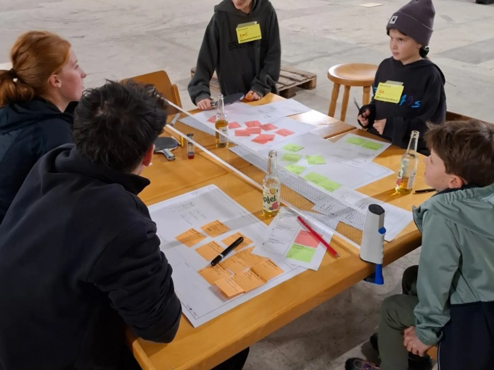 Mehrere Kinder arbeiten mit bunten Notizzetteln an einem Holztisch