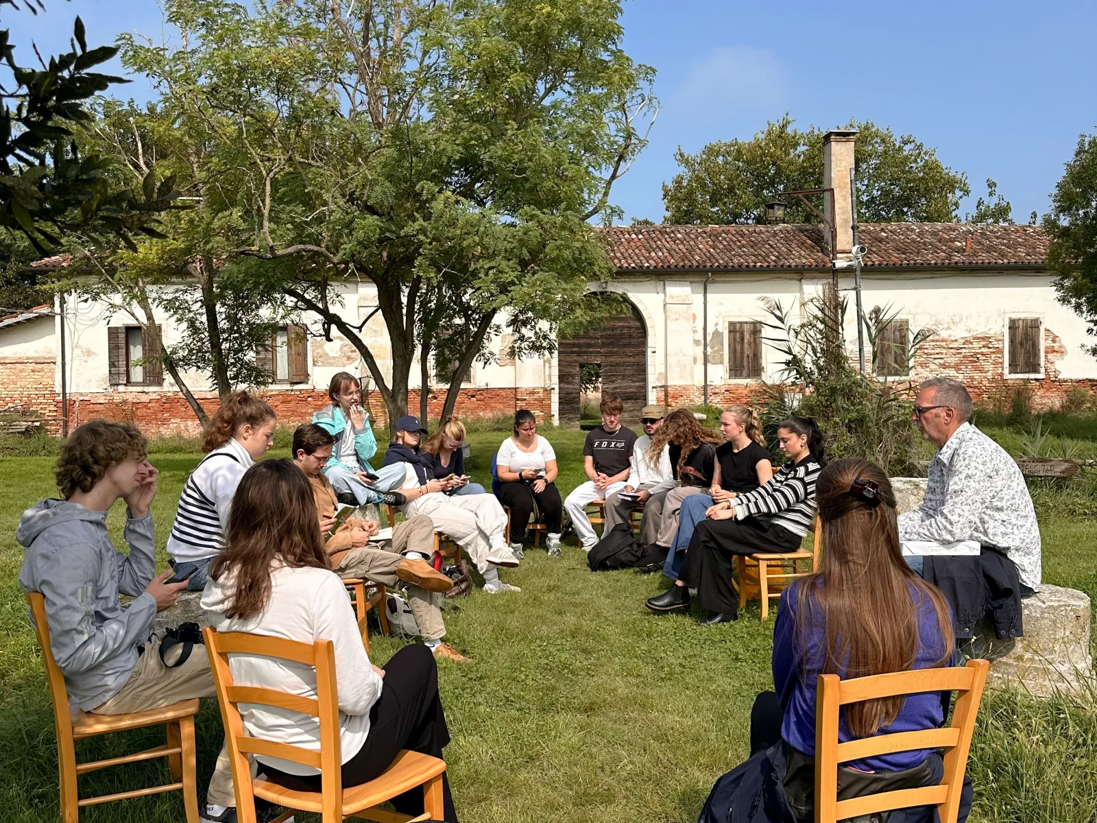 Gruppe junger Menschen sitzen im Freien in einem Stuhlkreis und diskutieren