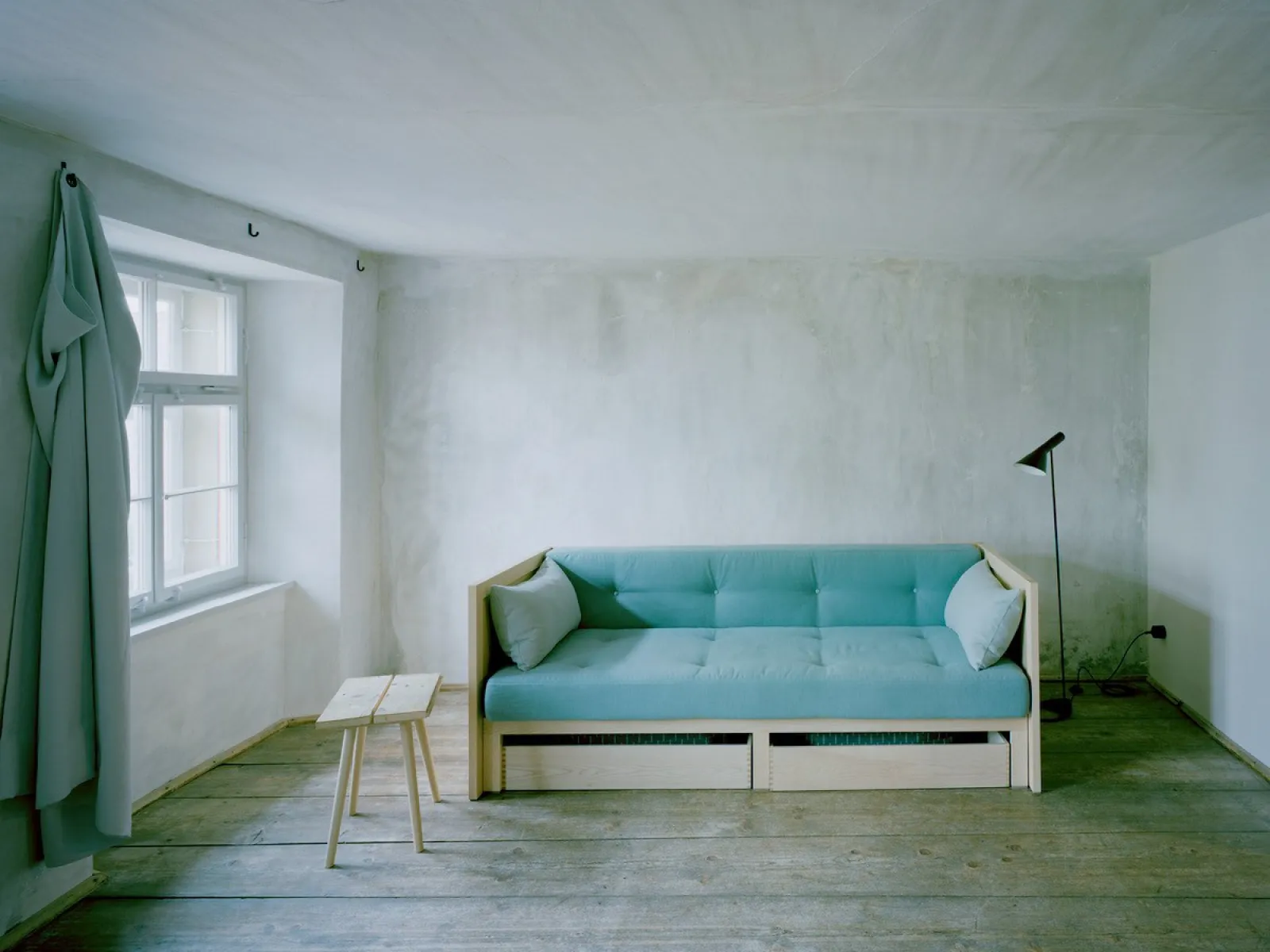 Minimalistischer Wohnraum mit Sofa und Fensterlicht in ruhiger Innenarchitektur