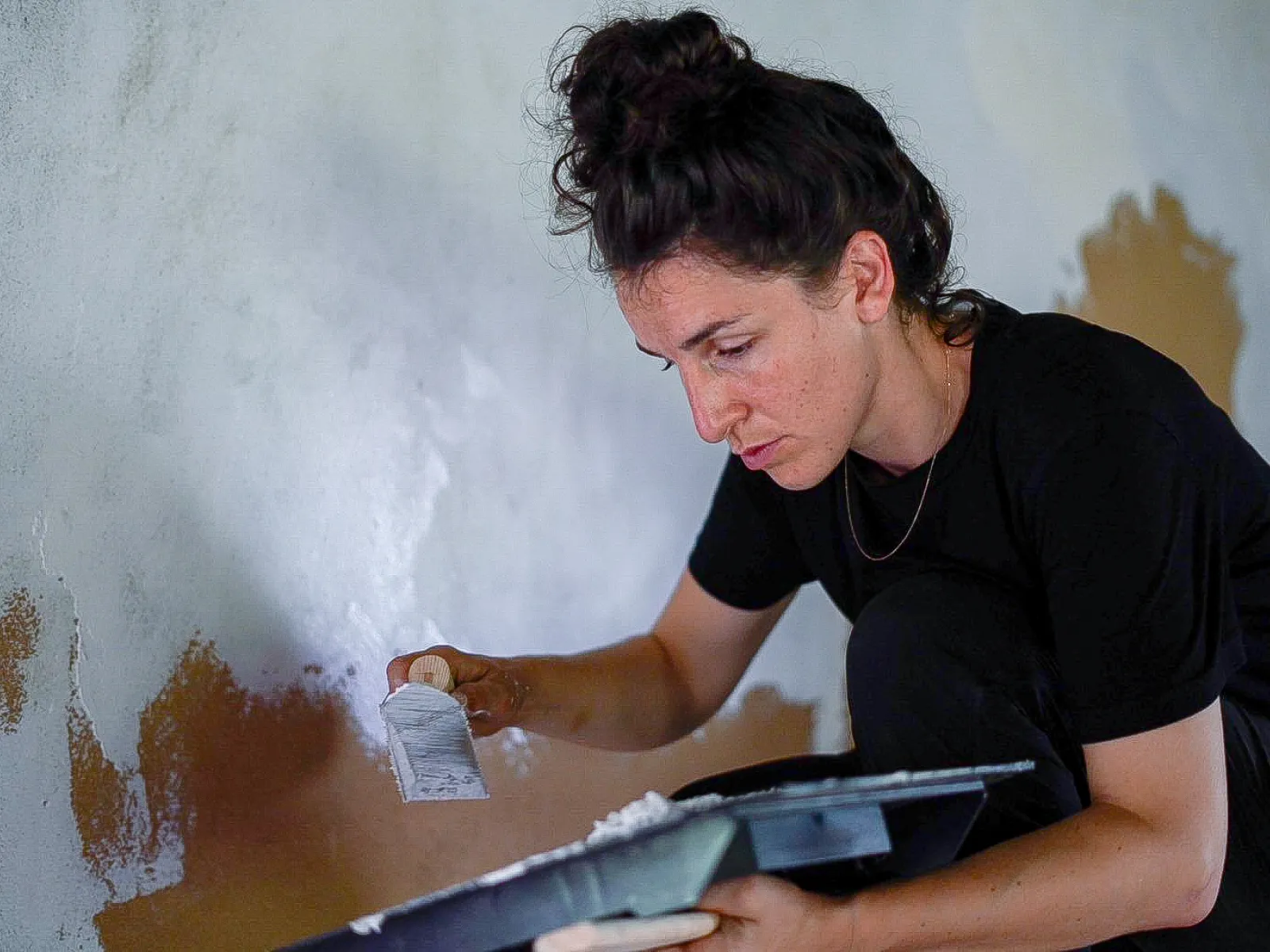 Person streicht Innenwand bei Renovationsarbeiten in historischem Gebäude, Detailaufnahme Handwerk und Architektur