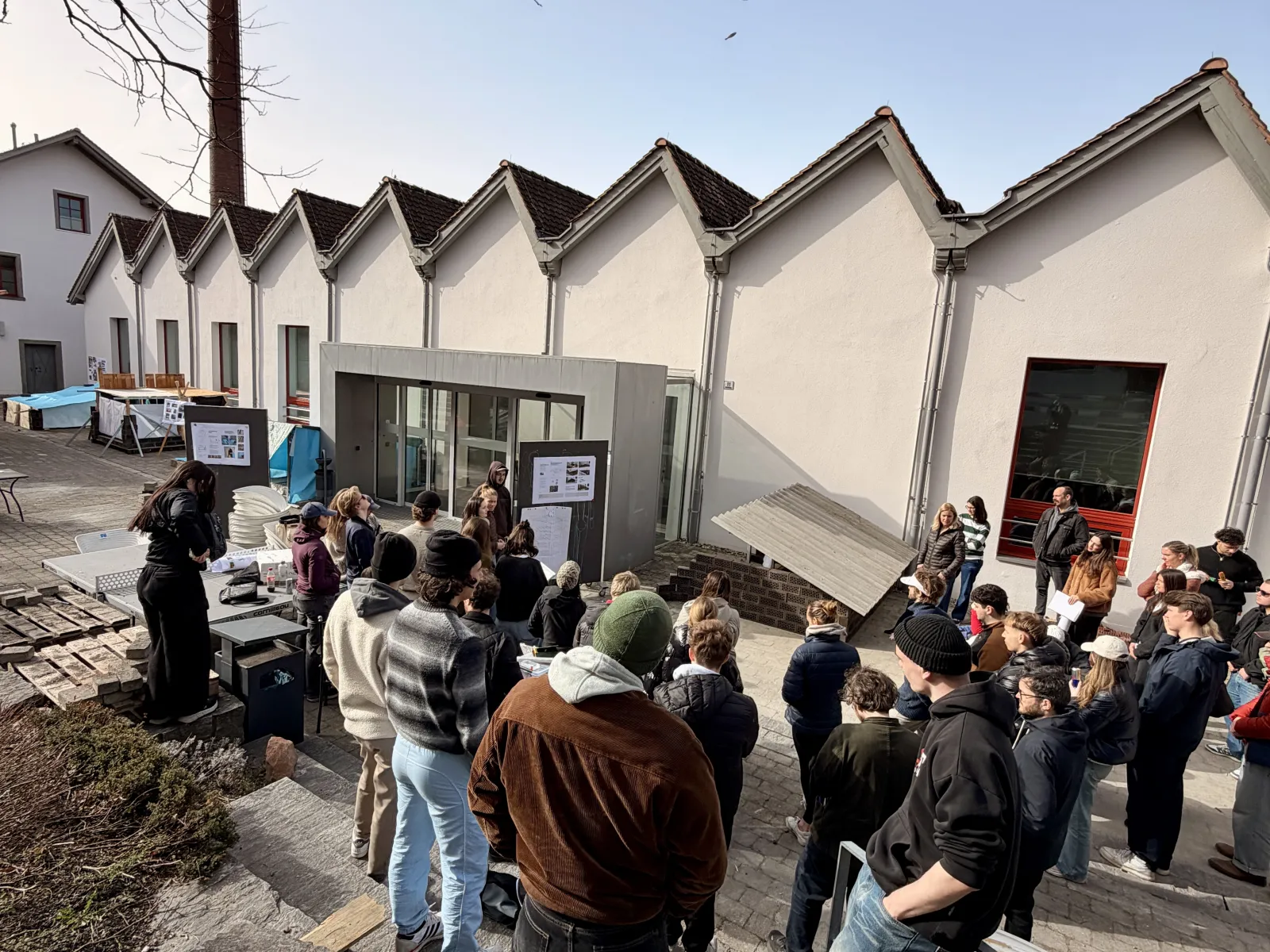 Mehrere junge Menschen neben einem Gebäude mit Shed-Dach