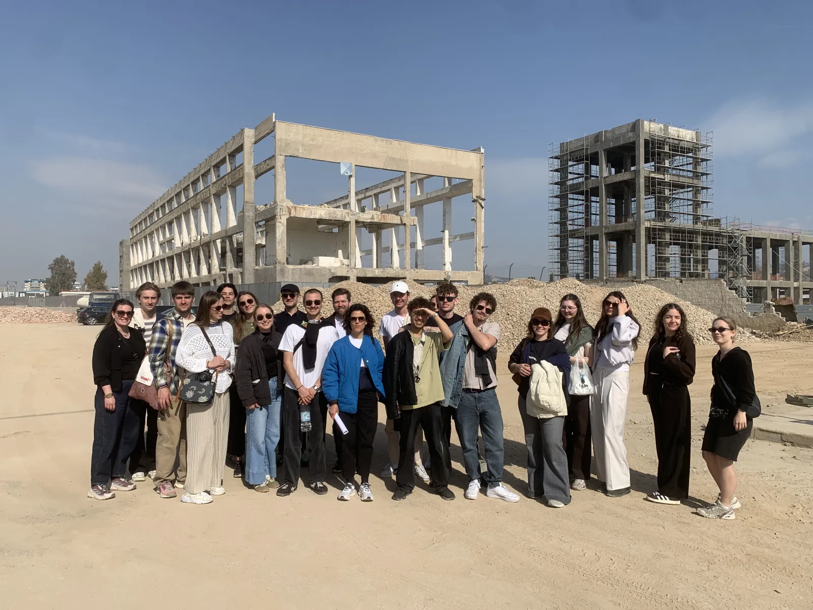 Gruppe von Studierenden schaut in die Kamera mit Betonkonstruktion im Hintergrund