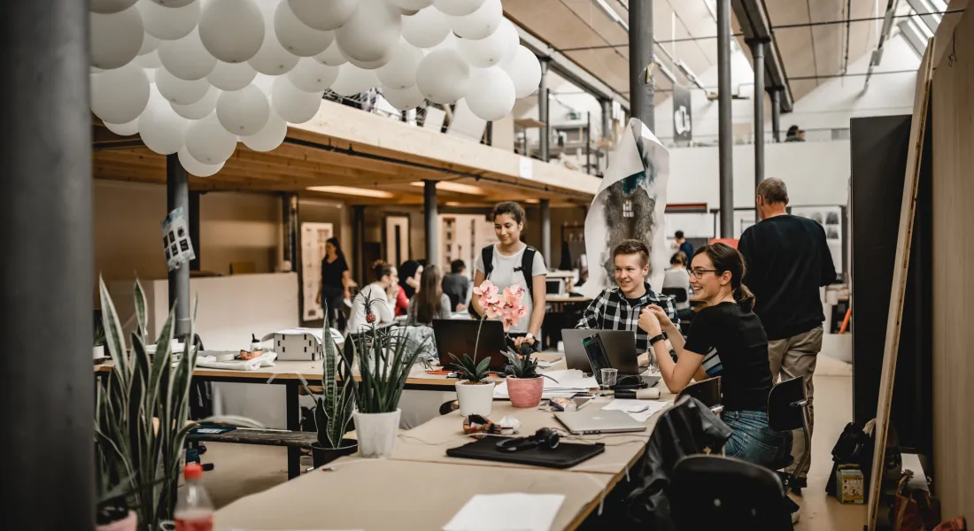 Lächelnde Studierende sitzen im Architekturatelier und arbeiten