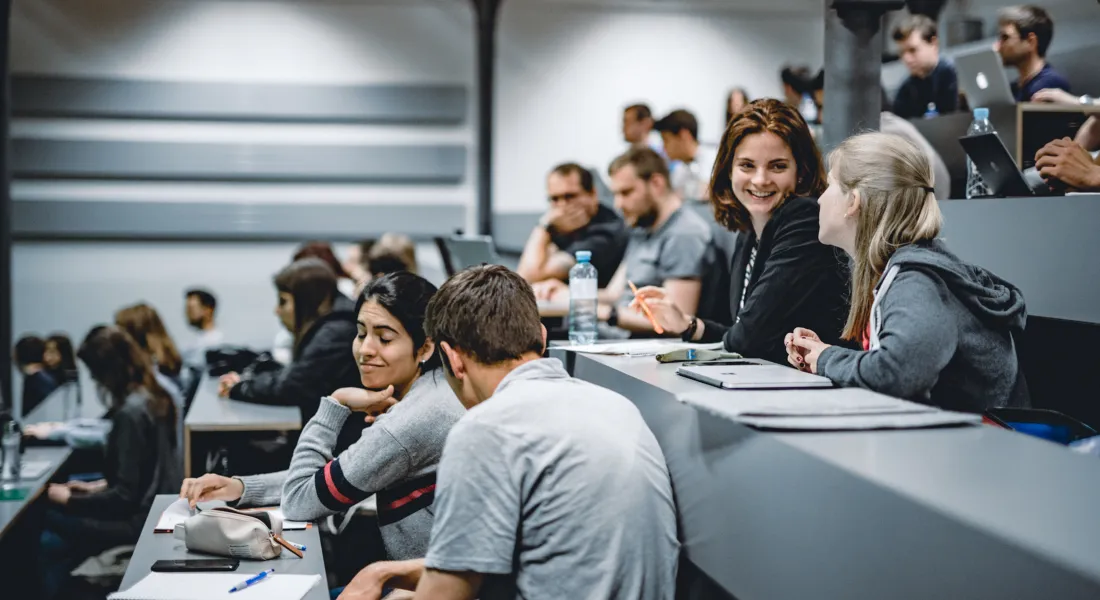 Studierende der Universität Liechtenstein sitzen im Hörsaal und unterhalten sich vor Beginn einer Vorlesung.