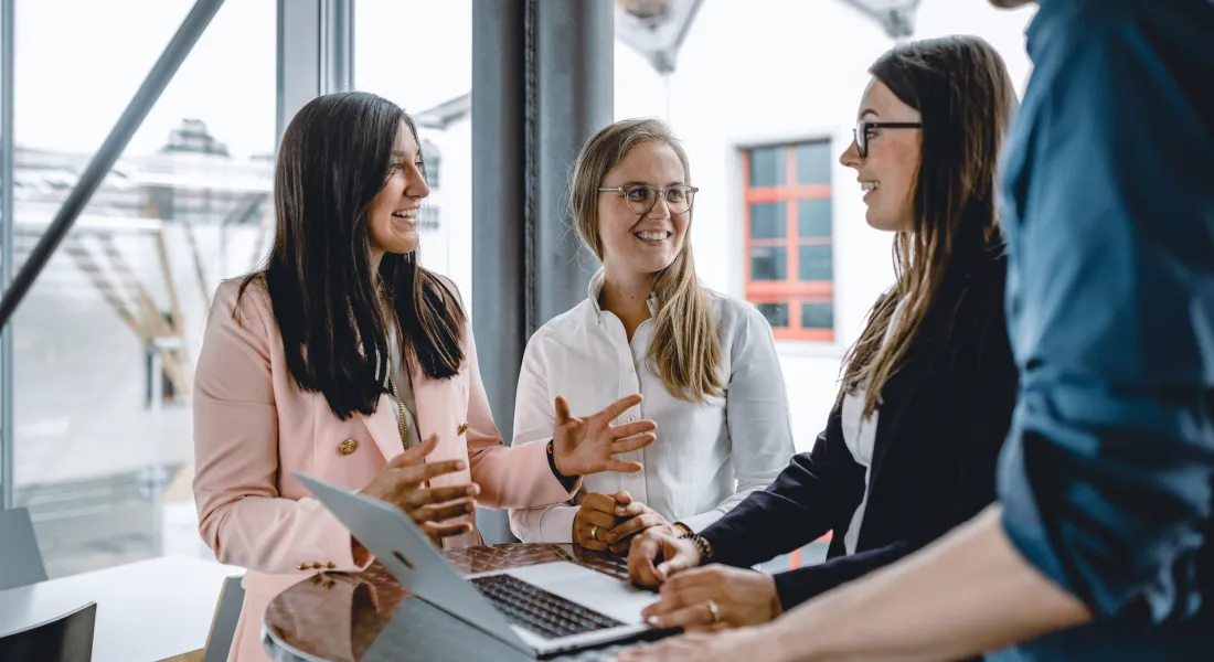 Eine Gruppe Studierende stehen im Gebäude der Universität Liechtenstein um einen Tisch