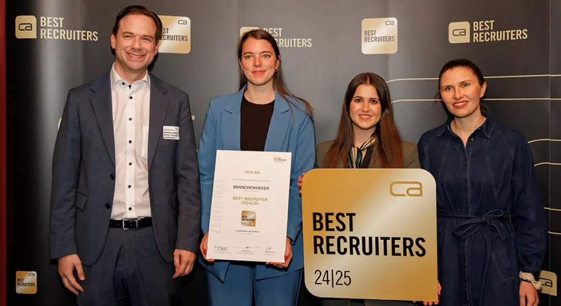 Vier Personen stehen vor einem Hintergrund mit dem Logo "Best Recruiters". Eine Person hält ein Zertifikat mit der Aufschrift "Branchen­sieger Best Recruiter 2024/25". Eine andere Person hält ein Schild mit dem gleichen Logo. Alle lächeln in die Kamera.