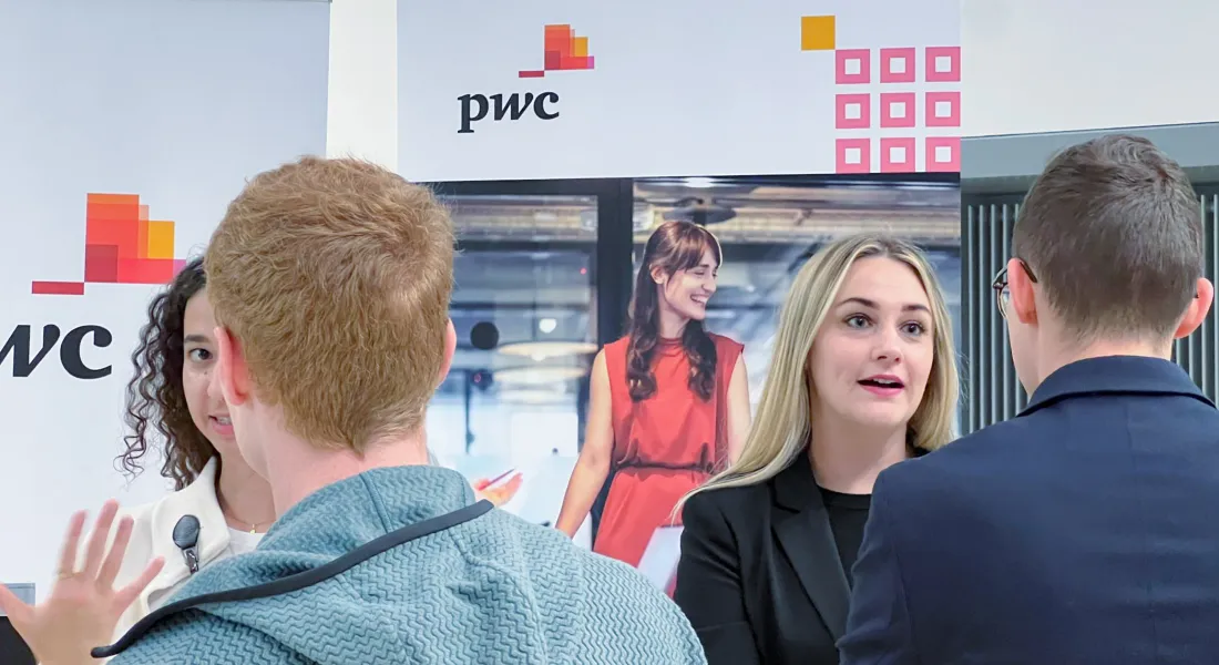 Studierende auf dem Karrieretag 2024 der Universität Liechtenstein vor dem Stand von pwc