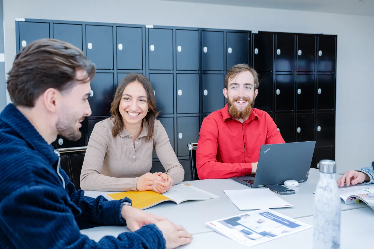 Studierende der Universität Liechtenstein arbeiten gemeinsam und lachen in entspannter Campus-Atmosphäre.