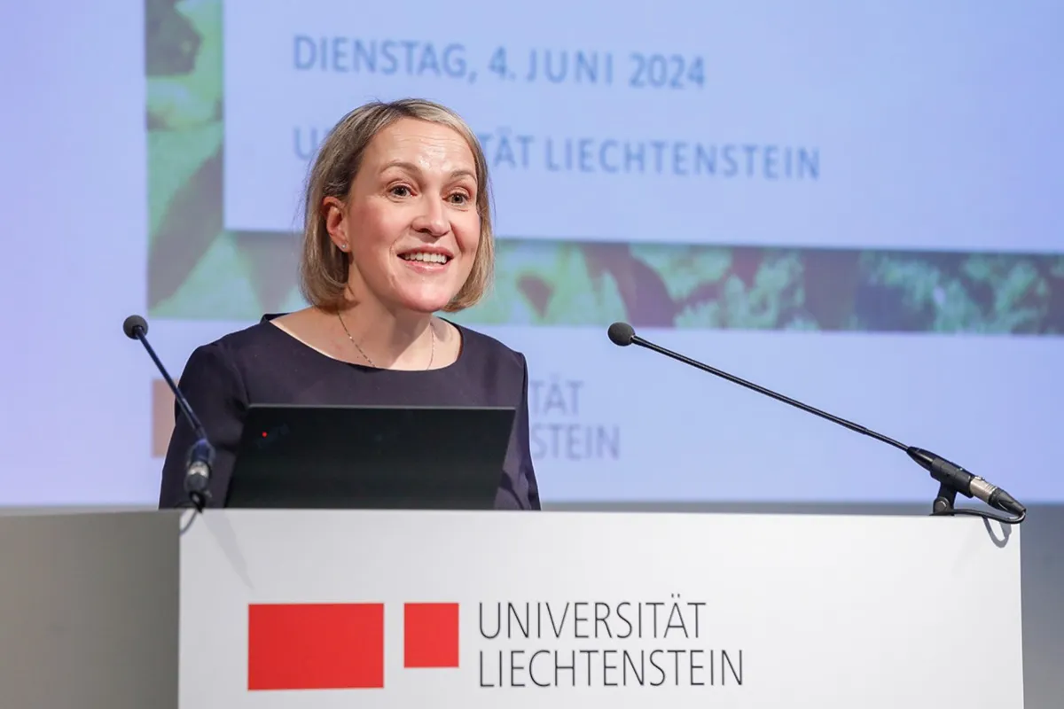 Eine Frau hält eine Rede am Rednerpult der Universität Liechtenstein. Im Hintergrund ist eine Präsentationsfolie mit dem Datum 4. Juni 2024 zu sehen.
