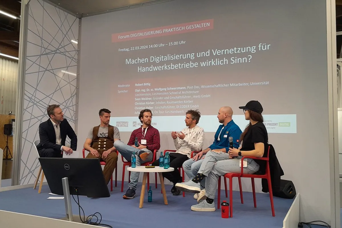 Podiumsdiskussion auf der Messe «Holz Handwerk 2024» in Nürnberg. Fünf Personen sitzen auf einer Bühne vor einer Leinwand mit dem Titel "Machen Digitalisierung und Vernetzung für Handwerksbetriebe wirklich Sinn?". Die Diskussion thematisiert die Rolle der Digitalisierung im Handwerk.