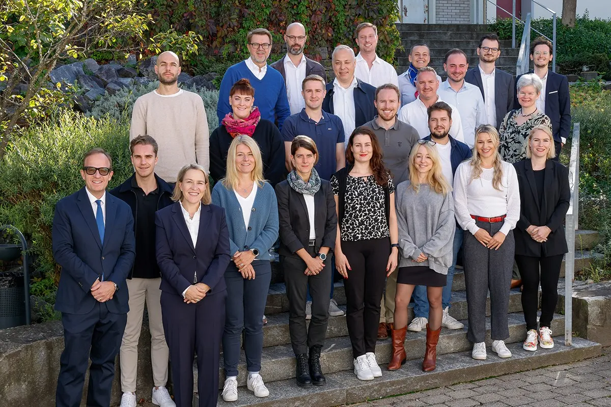 Gruppenfoto von Studierenden und Dozenten des Executive Master of Laws (LL.M.) im Gesellschafts-, Stiftungs- und Trustrecht an der Universität Liechtenstein. Die Gruppe steht auf einer Treppe im Freien, umgeben von grüner Vegetation.