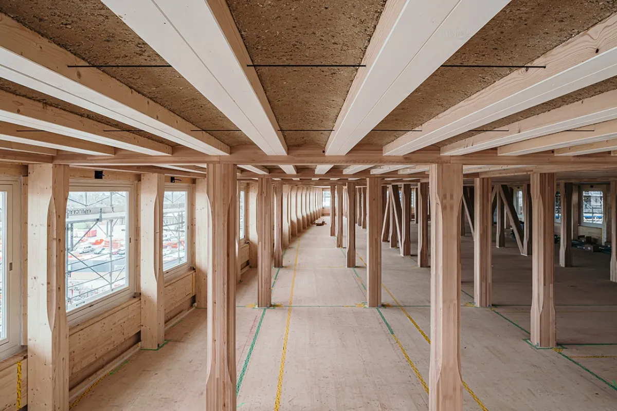 Innenansicht eines modernen Gebäudes mit Holzkonstruktion und Lehmboden, das den nachhaltigen Lehmbau am EARTH HUB der Universität Liechtenstein zeigt.
