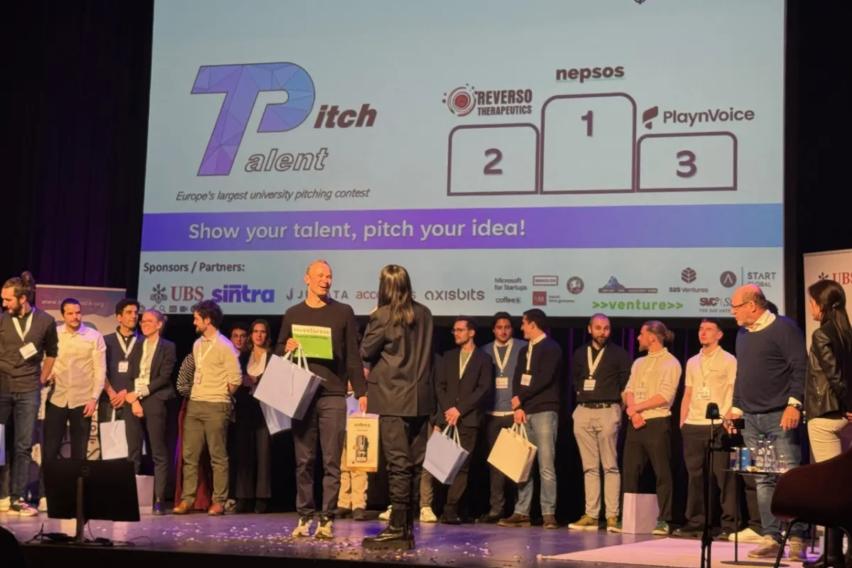 Eine Gruppe von Menschen steht auf einer Bühne beim Talent Pitch Switzerland im Volkshaus Zürich. Im Hintergrund ist eine Leinwand mit den Logos der Gewinner-Start-ups Reverso Therapeutics, Nepsos und PlaynVoice zu sehen. Die Veranstaltung wird von UBS gesponsert.