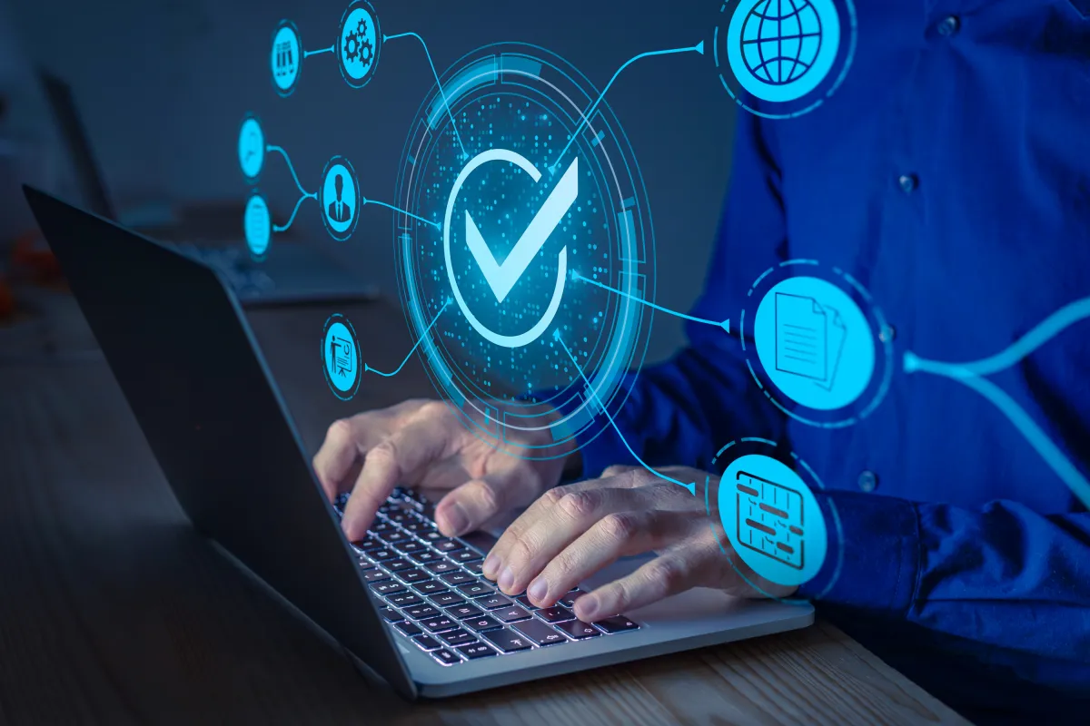 Person tippt auf Laptop mit eingeblendeten Symbolen für Business- und Datensysteme.