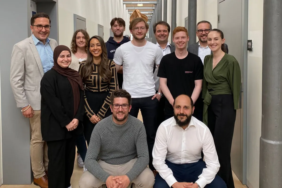 Eine Gruppe von Studierenden und Dozenten der Universität Liechtenstein posiert in einem Flur. Sie nehmen an der Accenture Campus Innovation Challenge teil, die sich auf künstliche Intelligenz und innovative Technologien konzentriert.
