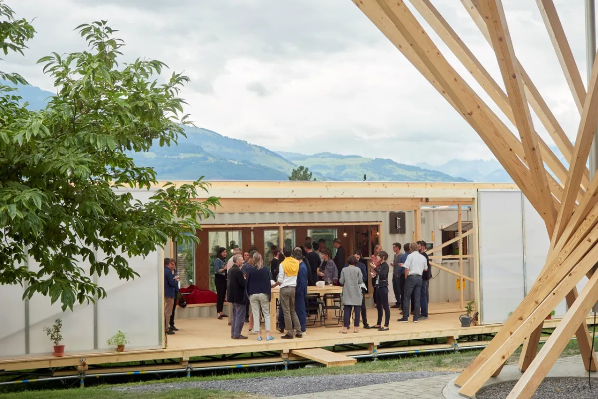 Aussenansicht des Base Camps, mit mehreren Menschen die davor stehen.