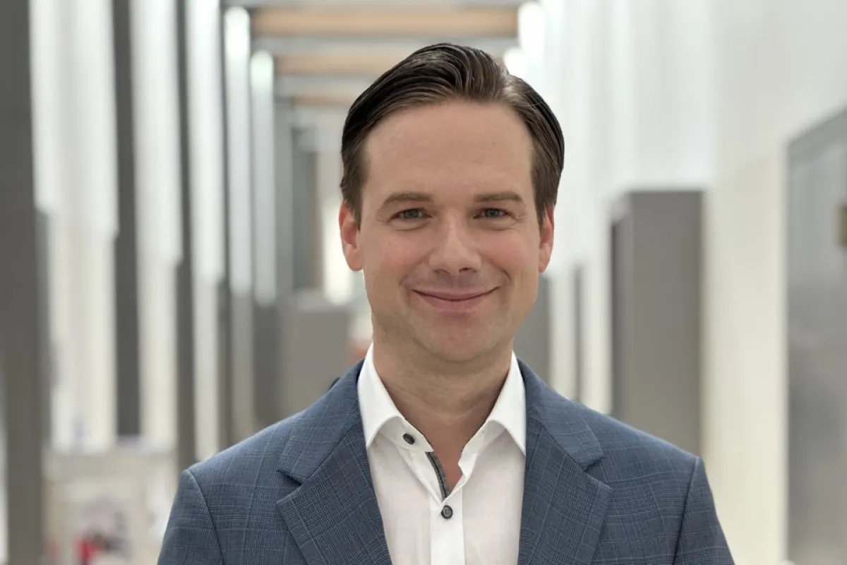 Ein Mann in einem blauen Anzug hält das Buch „Self-Leadership und Führung“ in einem modernen, hellen Flur.