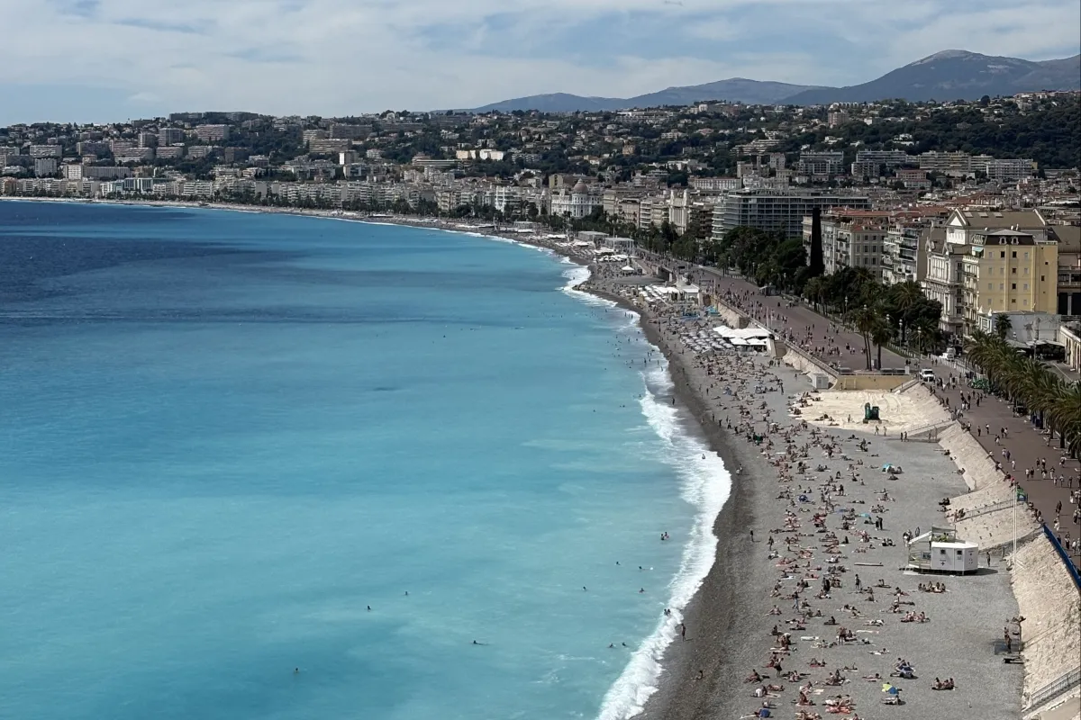 Grau wirkender Strand mit Blauem Wasser und vielen Menschen