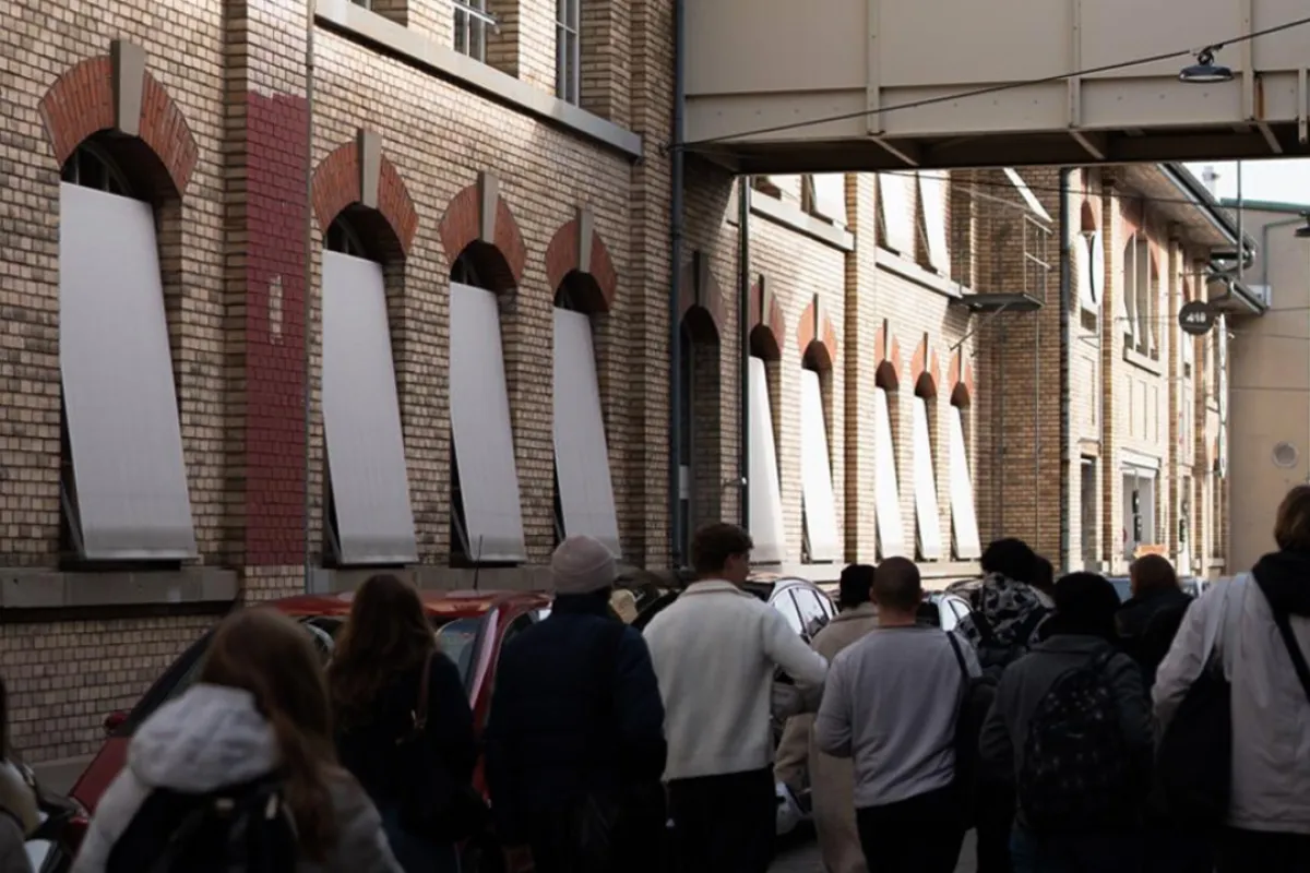 Mehrere Menschen laufen neben einem alten Fabriksgebäude