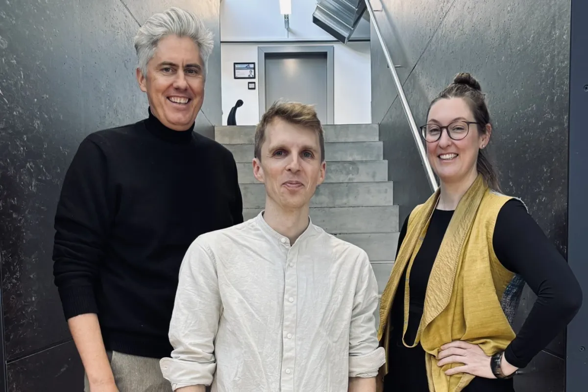 Drei Personen auf einer grau/schwarzen Treppe