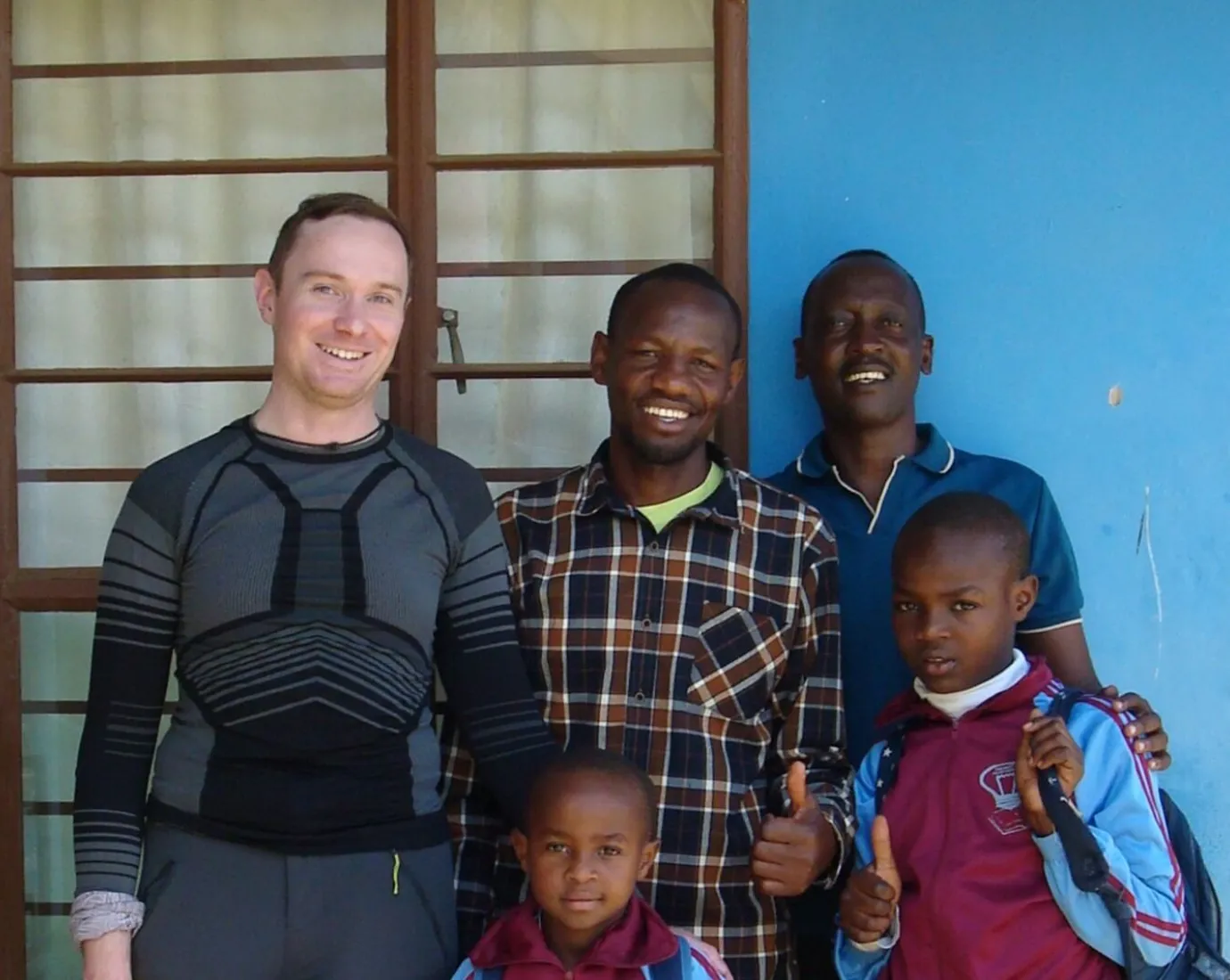 Gruppe von Personen steht vor einem blauen Gebäude.