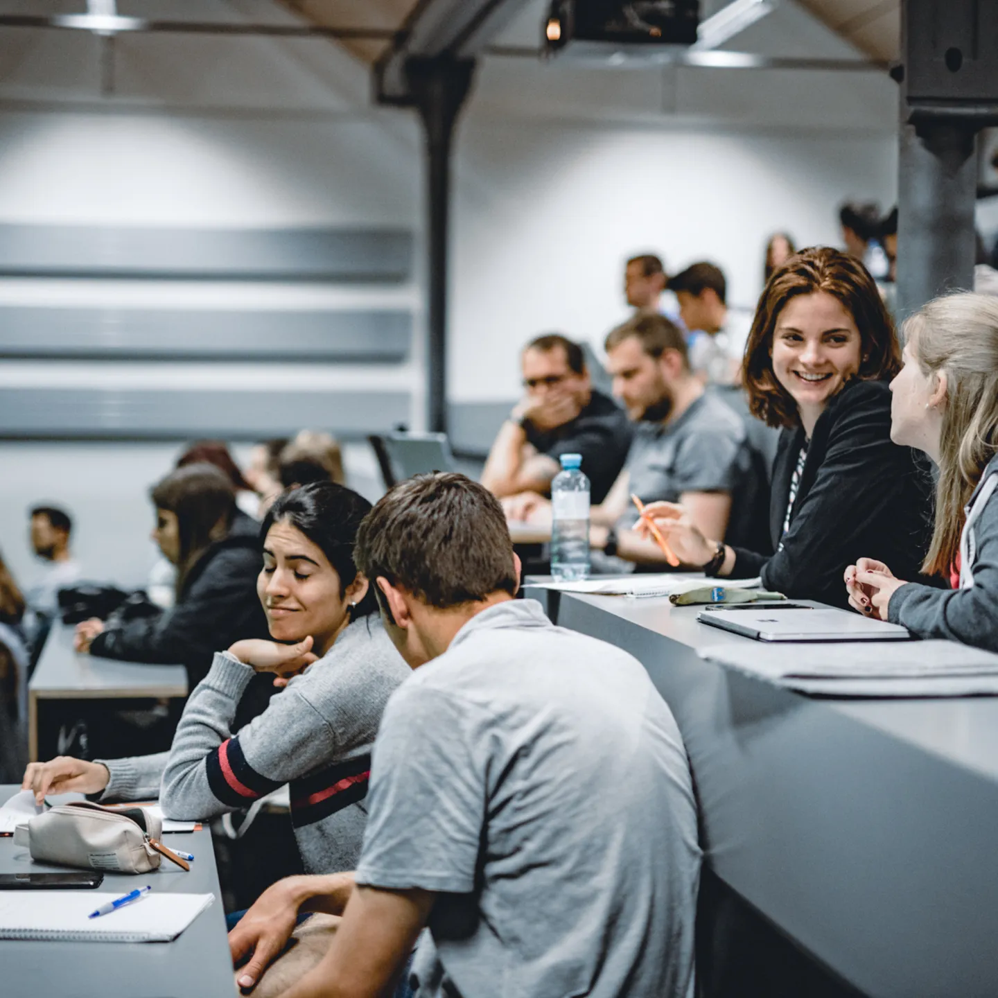 Studierende der Universität Liechtenstein sitzen im Hörsaal und unterhalten sich vor Beginn einer Vorlesung.