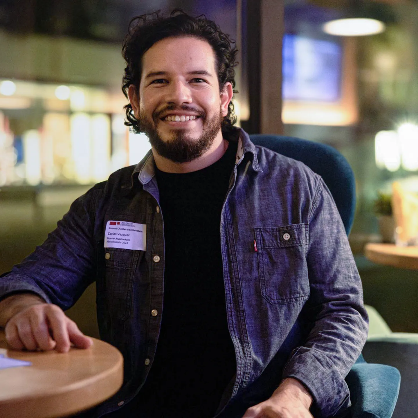 Lachender Teilnehmer des Alumni Treffens der Universität Liechtenstein in entspannter Abendatmosphäre