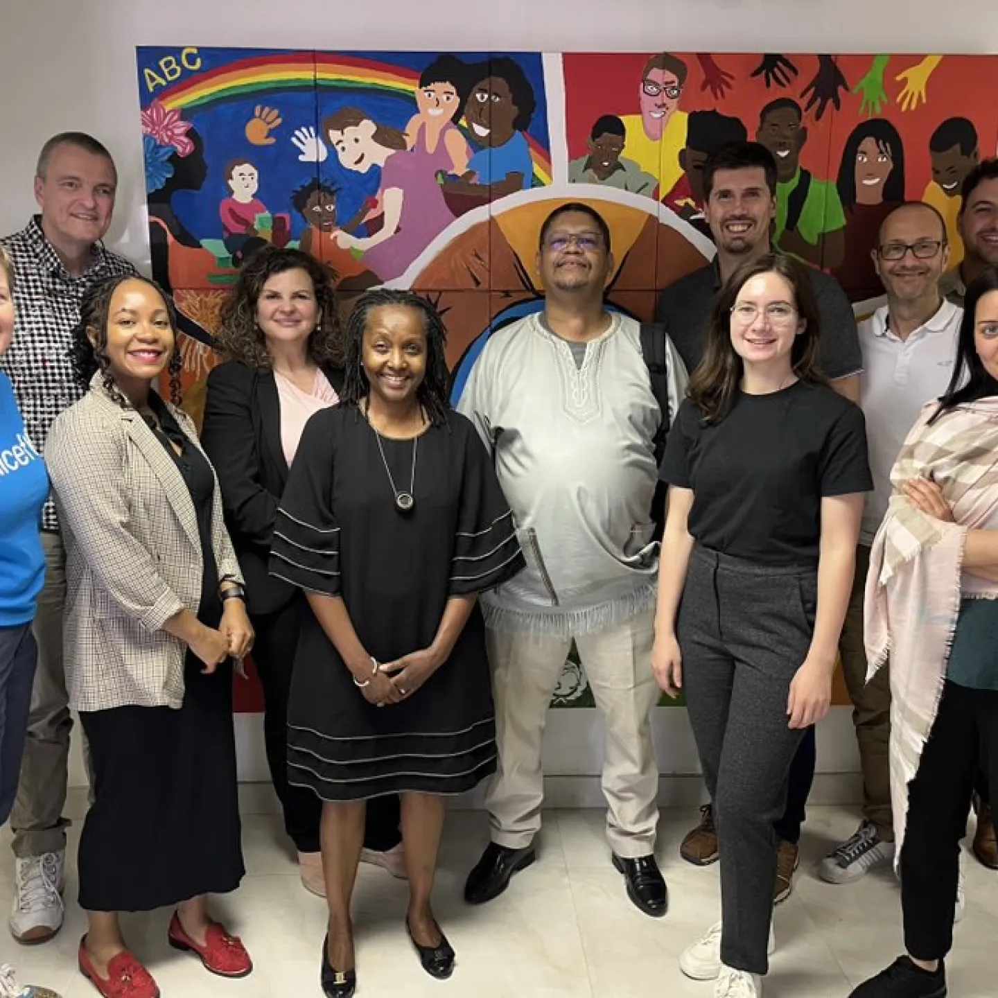 Eine Gruppe von Menschen steht lächelnd vor einem bunten Wandgemälde. Sie sind Teil einer Delegation der Universität Liechtenstein und Partnerorganisationen, die an einer Expedition nach Südafrika teilnehmen, um nachhaltige Finanzlösungen zu entwickeln.