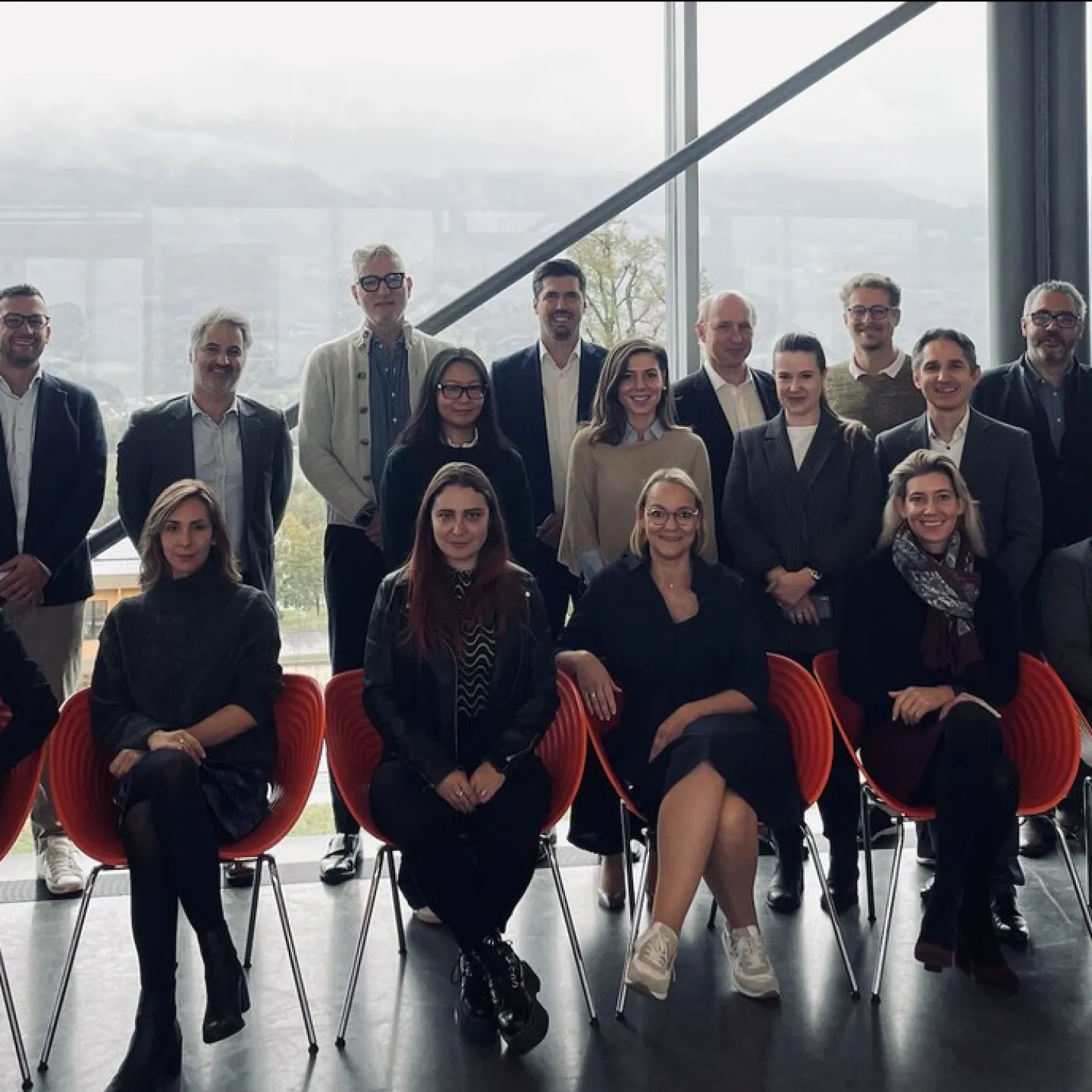 Gruppenfoto von Teilnehmenden der MiCAR Expert Roundtable Series an der Universität Liechtenstein. Die Personen stehen und sitzen in zwei Reihen vor einer großen Fensterfront mit Blick auf eine bergige Landschaft.