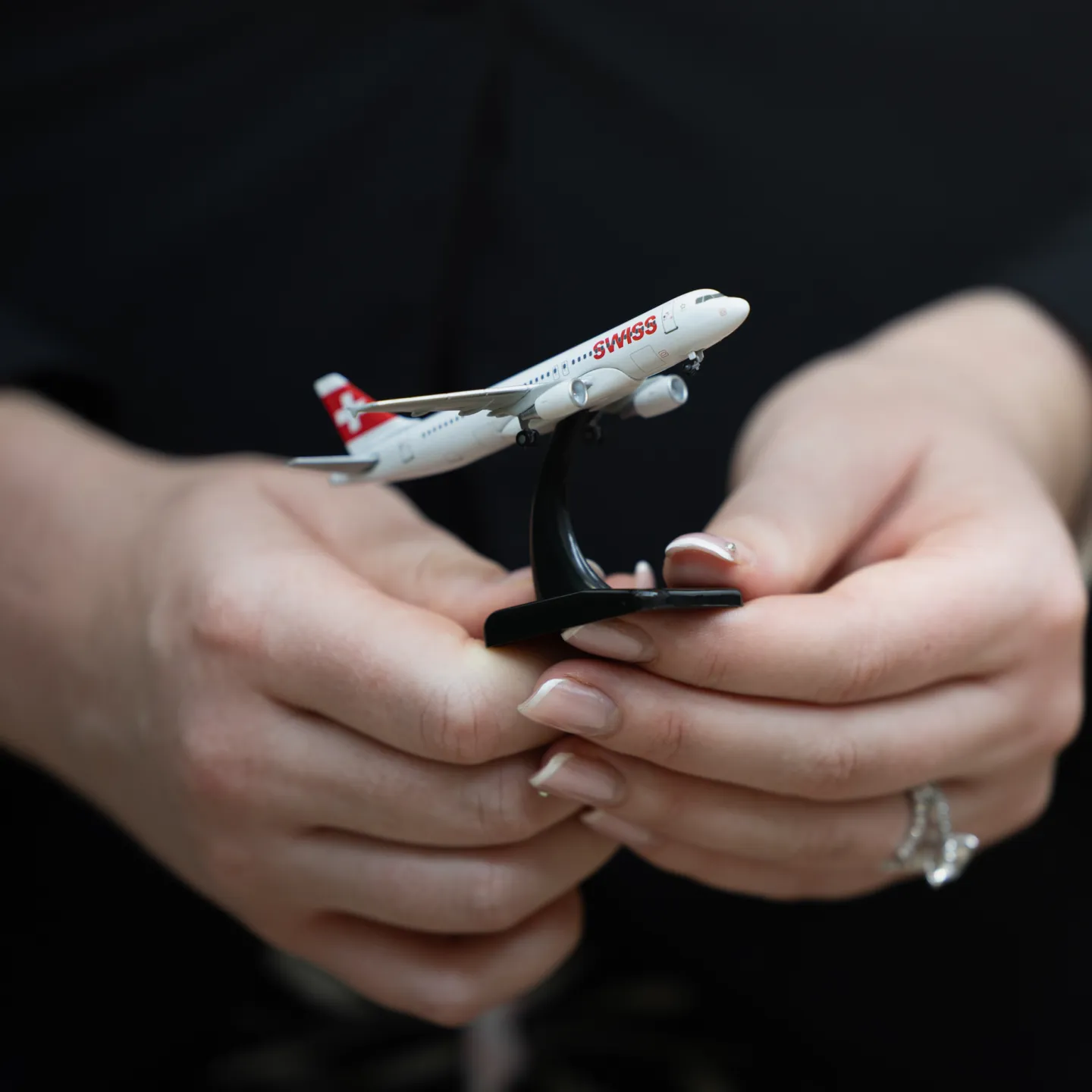 Hände halten Modellflugzeug der Fluggesellschaft SWISS.