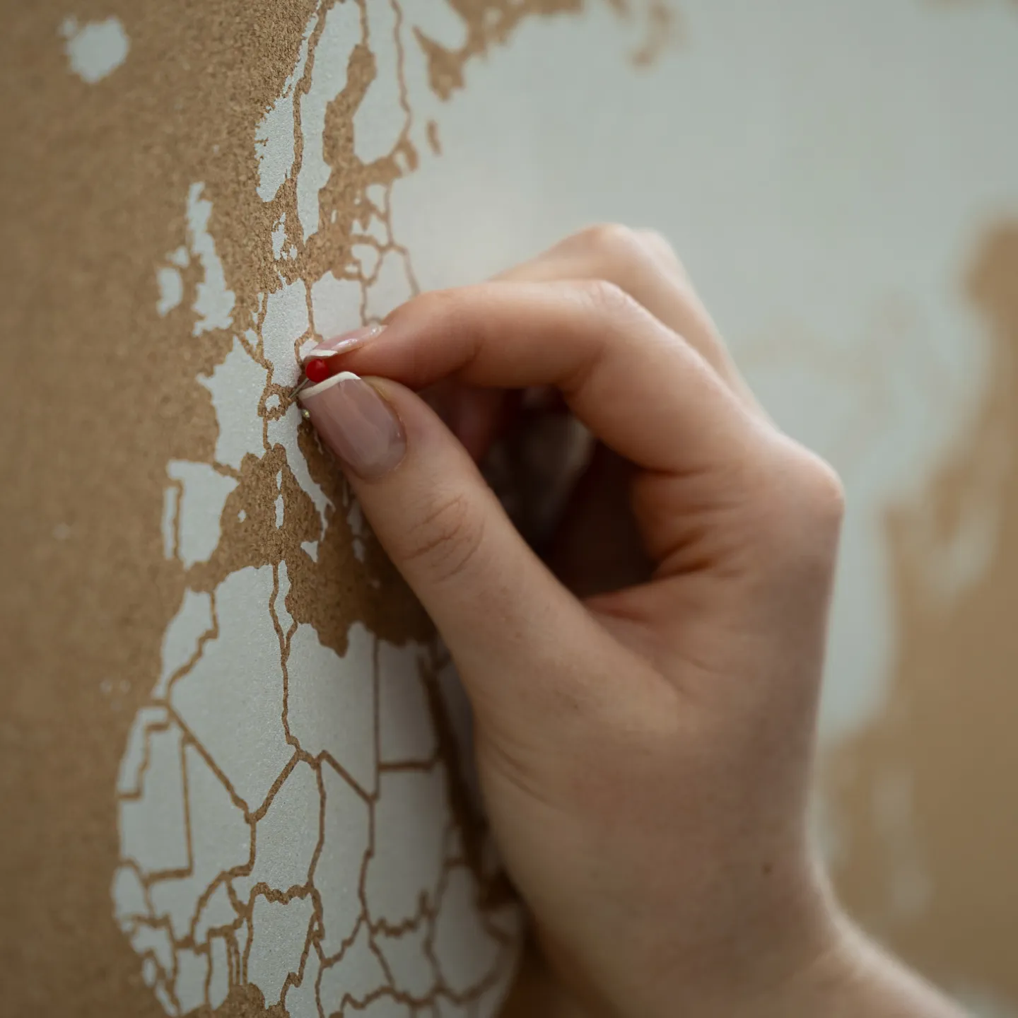 Hand steckt roten Pin in Europakarte zur Markierung eines Ortes.