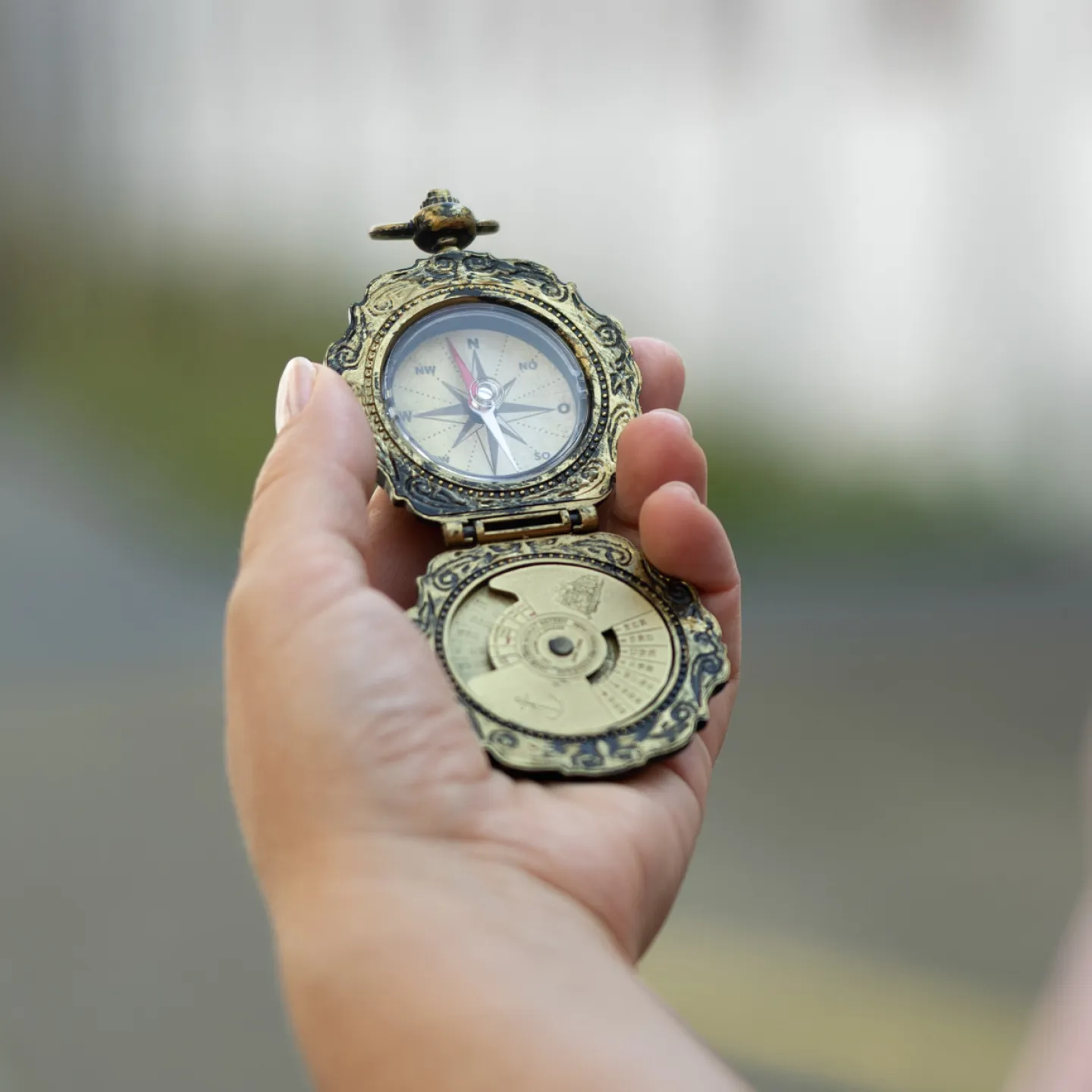 Hand hält antiken Kompass im Außenbereich der Universität Liechtenstein.