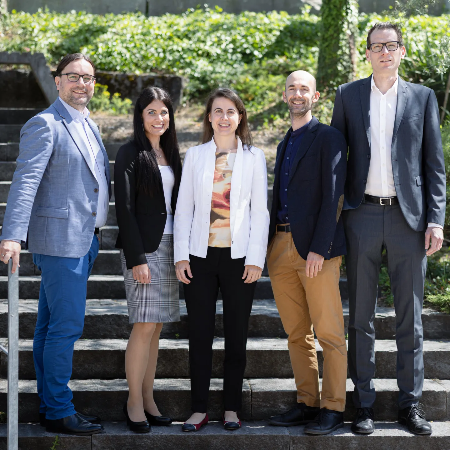 Dozierende und Mitarbeitende der Business School der Universität Liechtenstein posieren gemeinsam für ein Gruppenfoto im Freien.