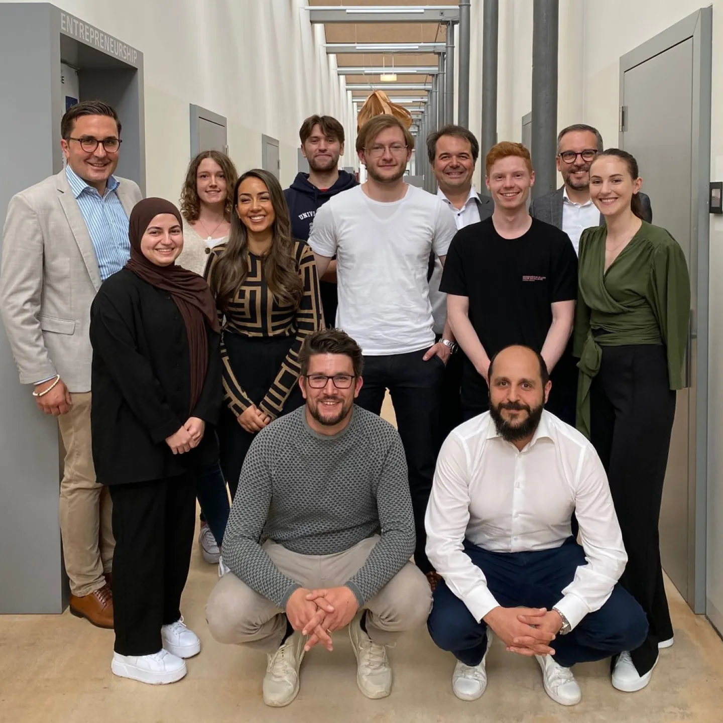 Eine Gruppe von Studierenden und Dozenten der Universität Liechtenstein posiert in einem Flur. Sie nehmen an der Accenture Campus Innovation Challenge teil, die sich auf künstliche Intelligenz und innovative Technologien konzentriert.