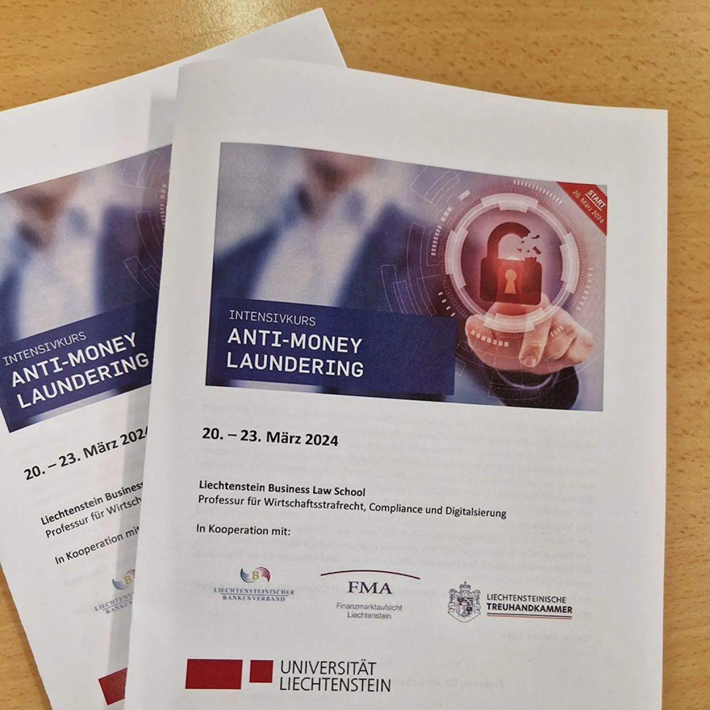 Broschüren des Intensivkurses „Anti-Money Laundering“ der Universität Liechtenstein, datiert auf 20.–23. März 2024, mit Logos von Kooperationspartnern und einem digitalen Schloss-Symbol auf dem Cover.