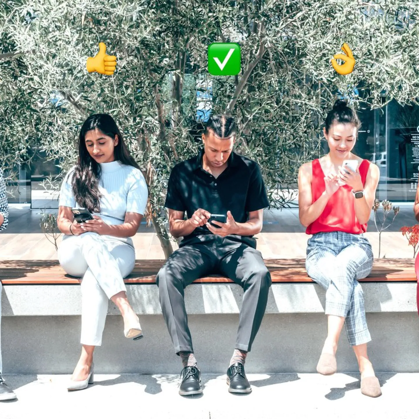 Fünf Personen sitzen auf einer Bank im Freien und schauen auf ihre Smartphones. Über ihren Köpfen sind verschiedene Emojis zu sehen, die Emotionen und Gesten darstellen. Im Hintergrund sind Bäume und ein Gebäude sichtbar.