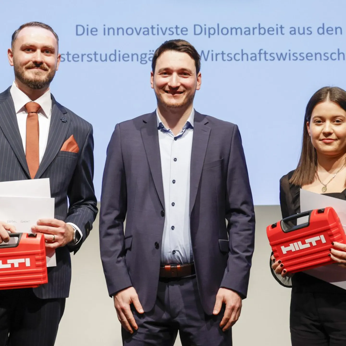 Tobias Zangerl mit Ermal Gashi und Laura Boltizar welche einen Hilti Koffer halten.