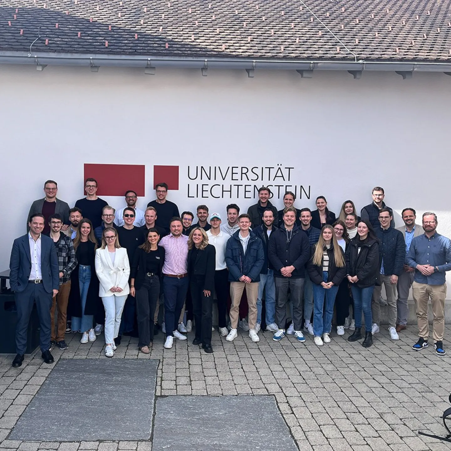 Gruppe von Studierenden und Jury-Mitgliedern des Startup Labs vor dem Gebäude der Universität Liechtenstein, aufgenommen bei den Mid-Term-Präsentationen des Masterstudiengangs Entrepreneurship und Management.