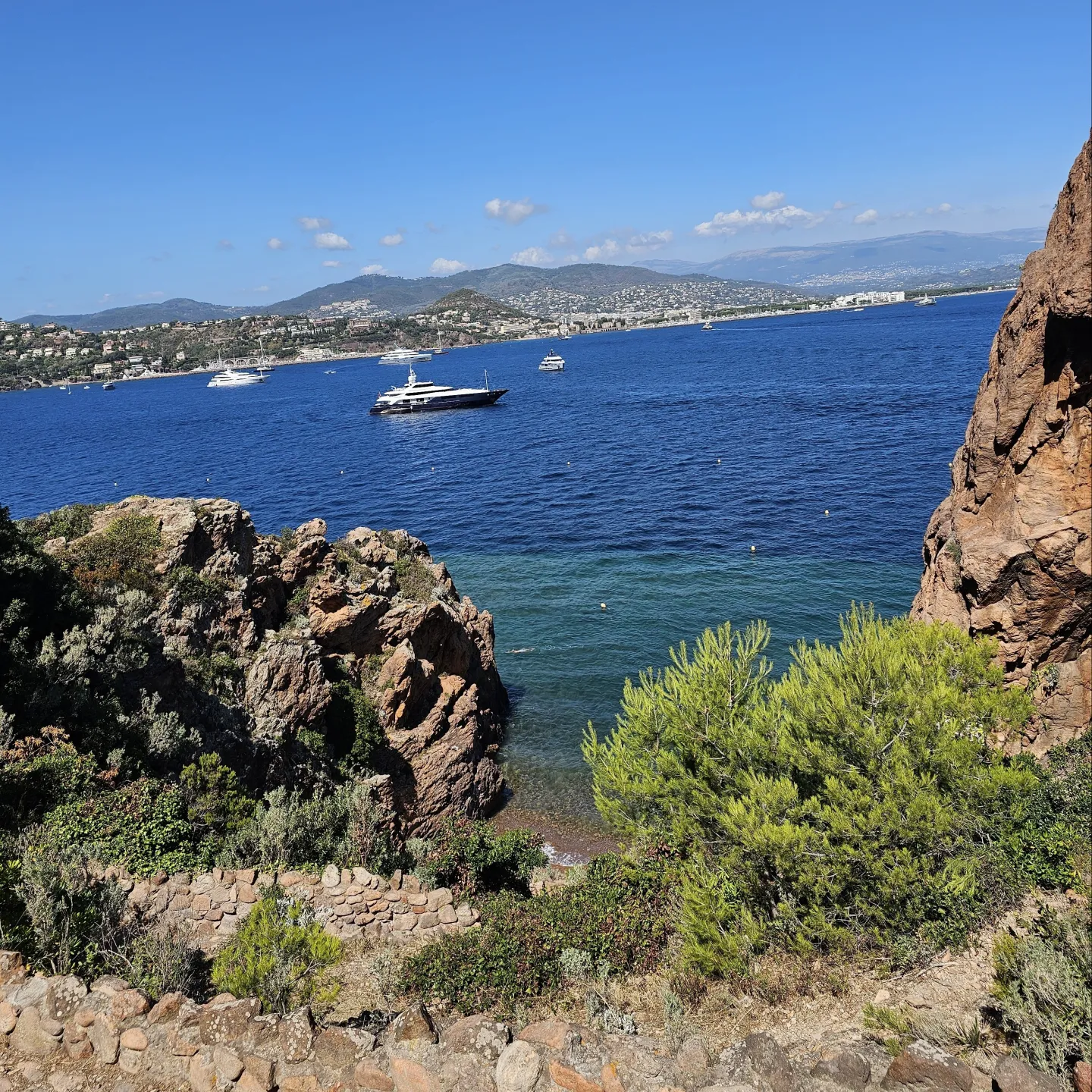 Bucht mit blauem Wasser, Felsen und ein paar Yachten
