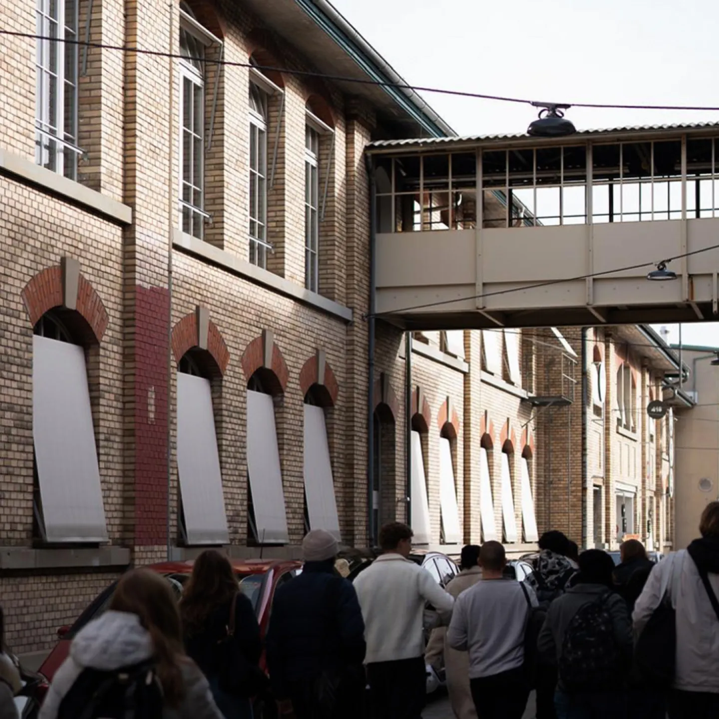 Mehrere Menschen laufen neben einem alten Fabriksgebäude